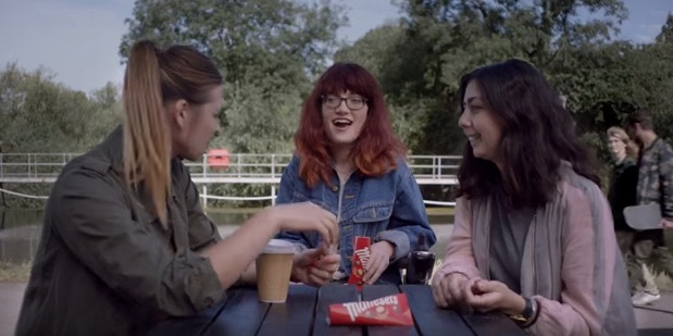Three teenage girls sitting at a picnic table laughing