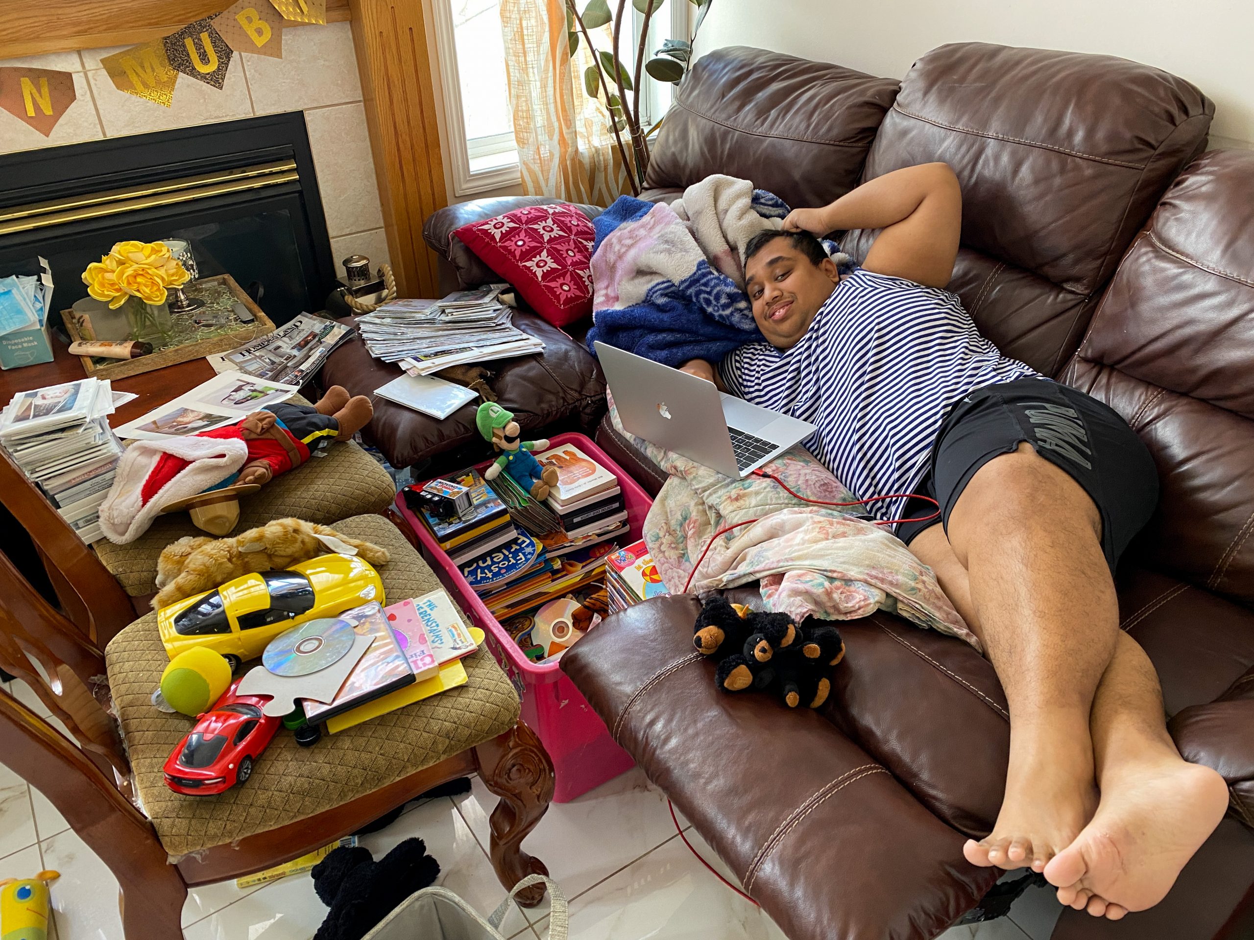 Ridwan lying down on the couch with the laptop on front of him