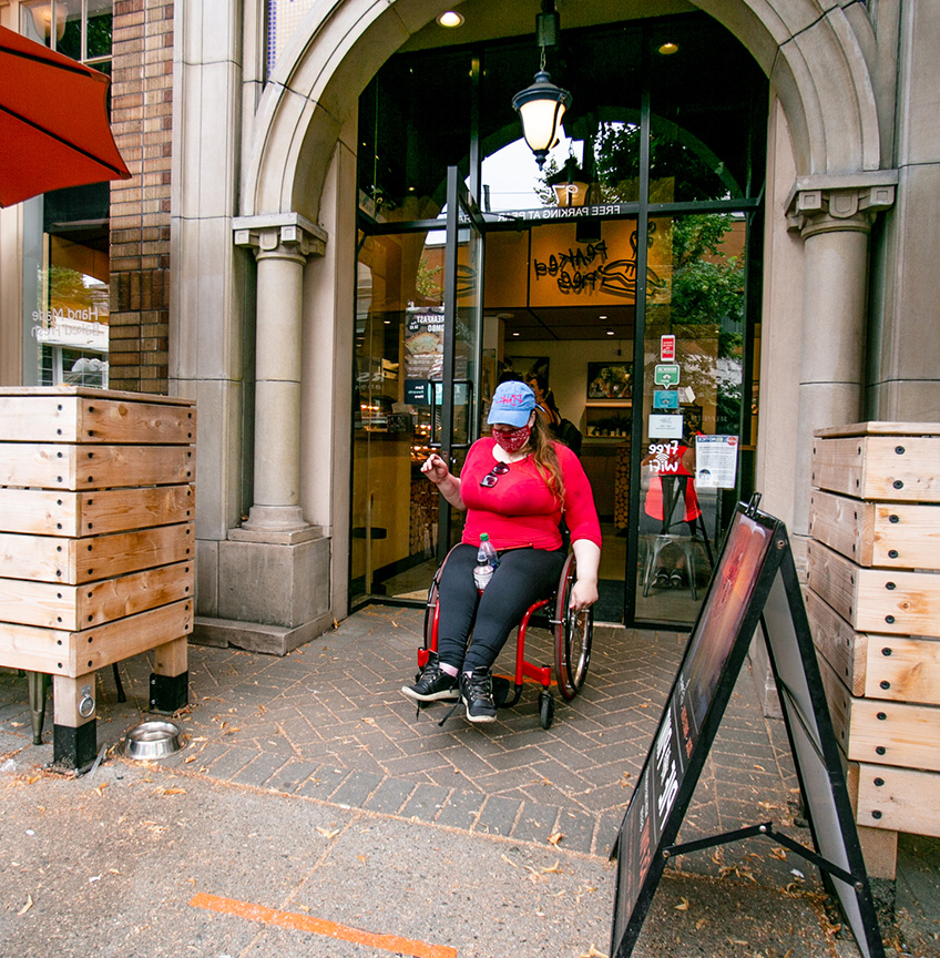 femme en fauteuil roulant sortant d'un magasin