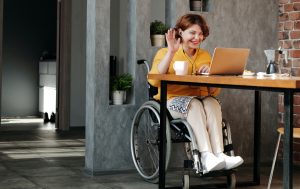 Woman sitting on wheelchair joins a virtual meeting on her laptop