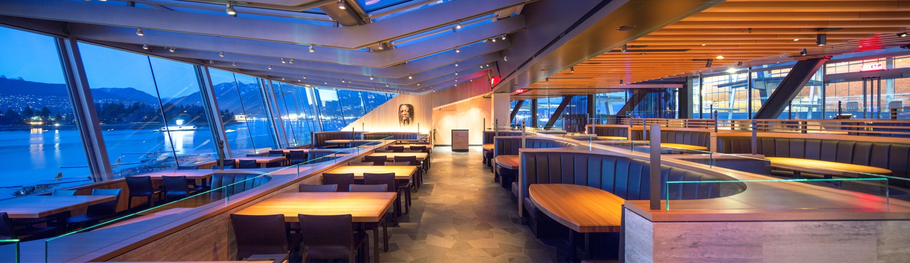 evening interior of cactus club cafe with hardwood furnishing overlooking a panoramic window view of the ocean