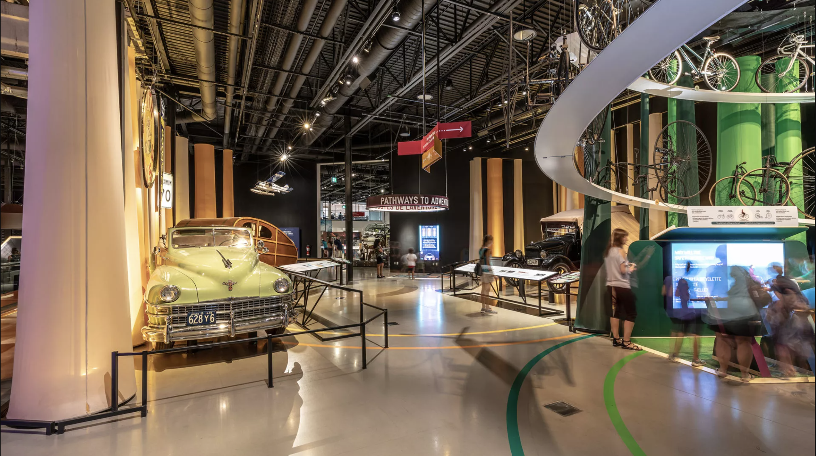 interior of science museum exhibit with dramatic lighting and an old car on display