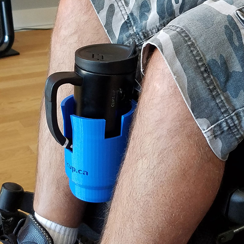 cup attachment gripped on to wheelchair holding a hot mug