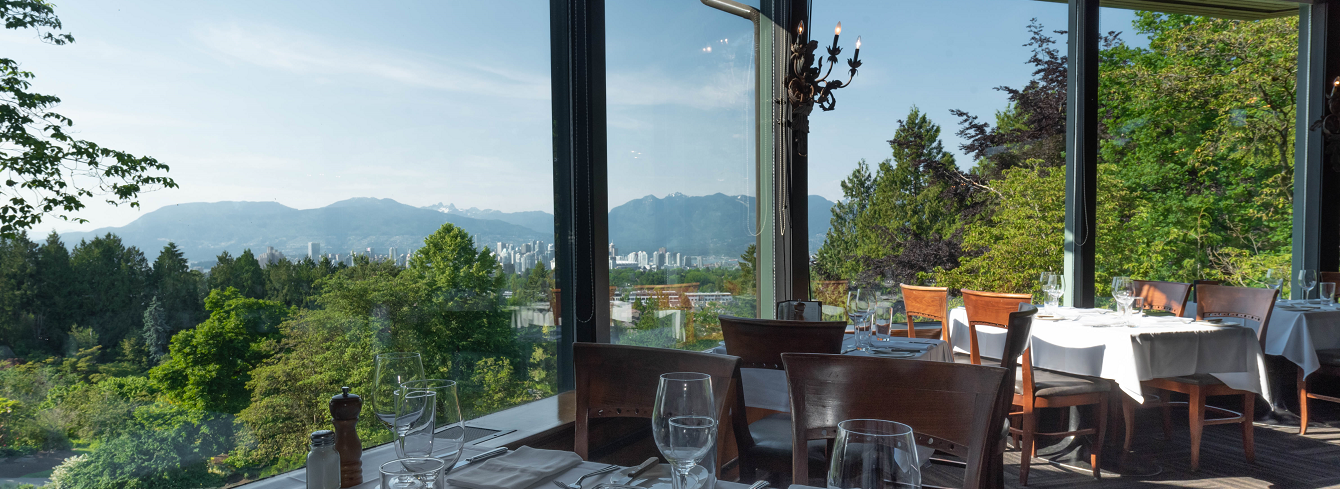 interior seasons in the park restaurant with an entire wall of windows overlooking a lush green park and mountain view