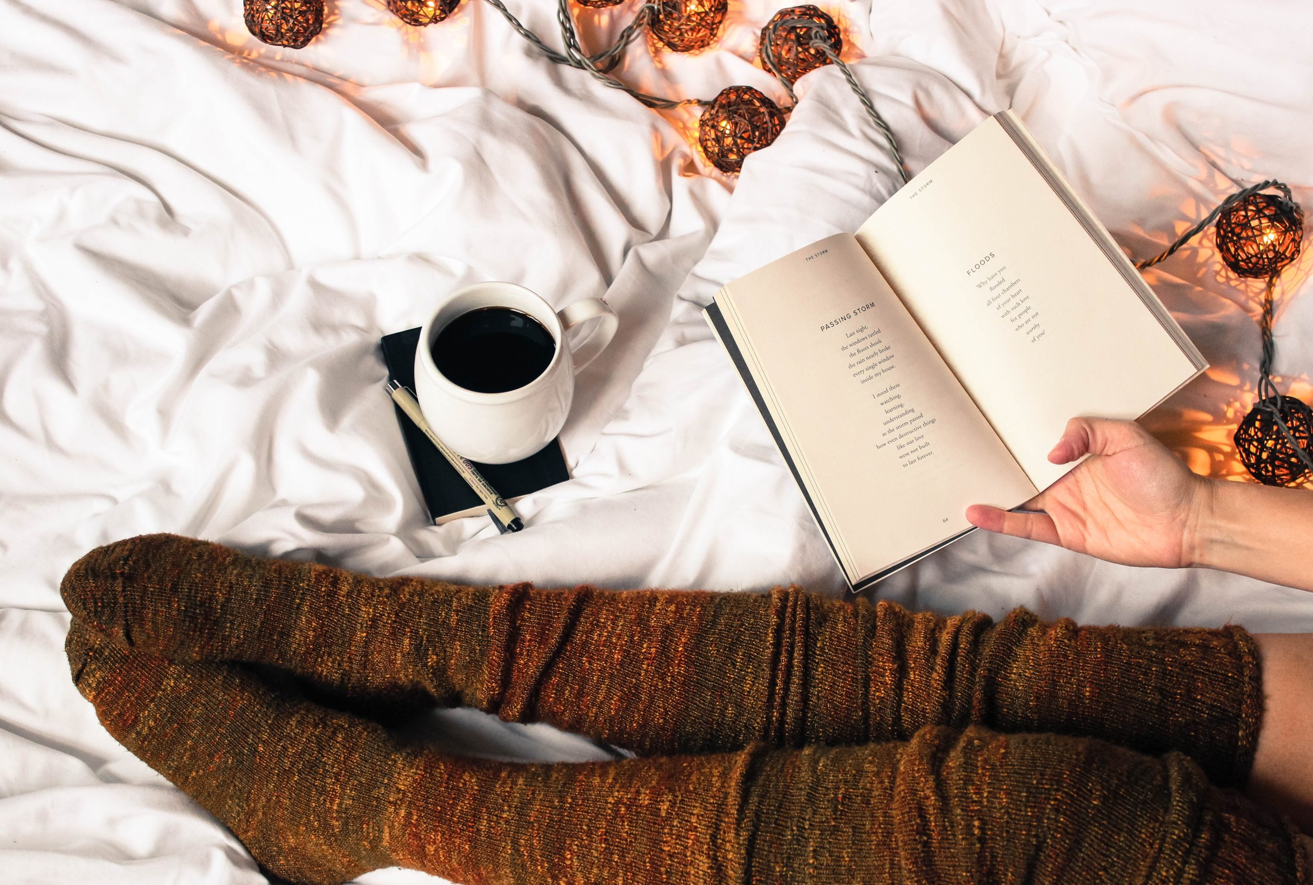 image of someone in wool socks in bed with a hot drink and a journal