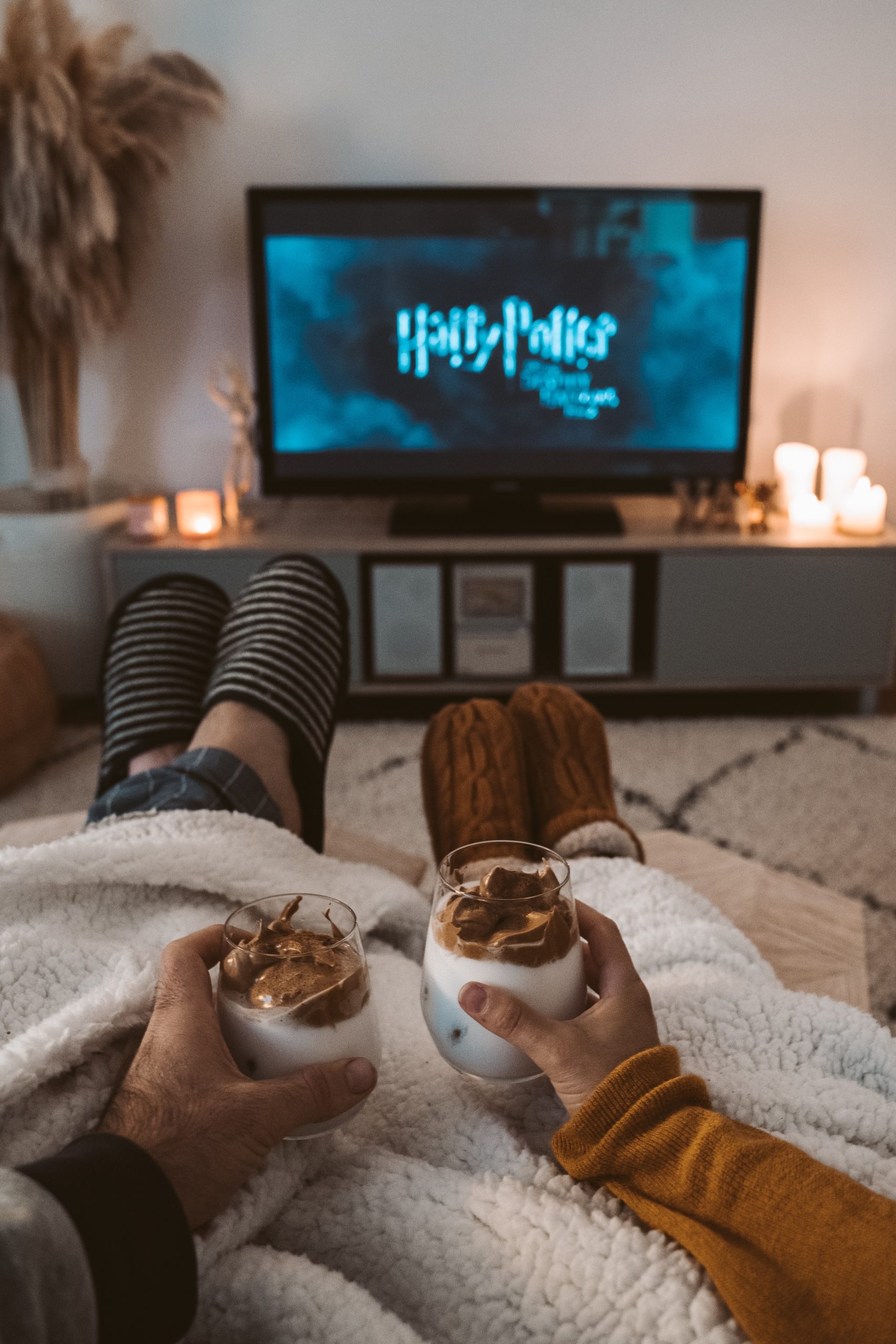 two people wear slippers under blankets watching harry potter