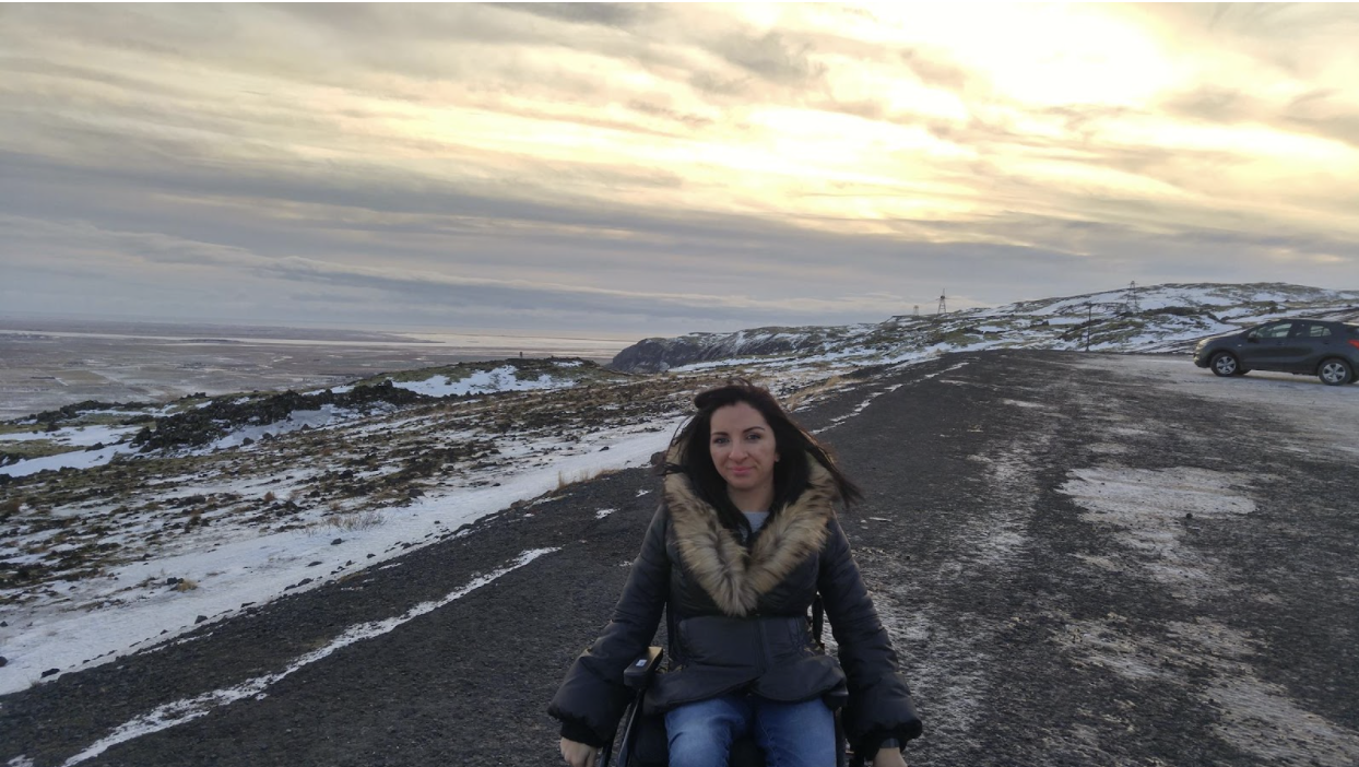 nikoletta in the middle of the street, scenic view of iceland with pockets of snow in the background.