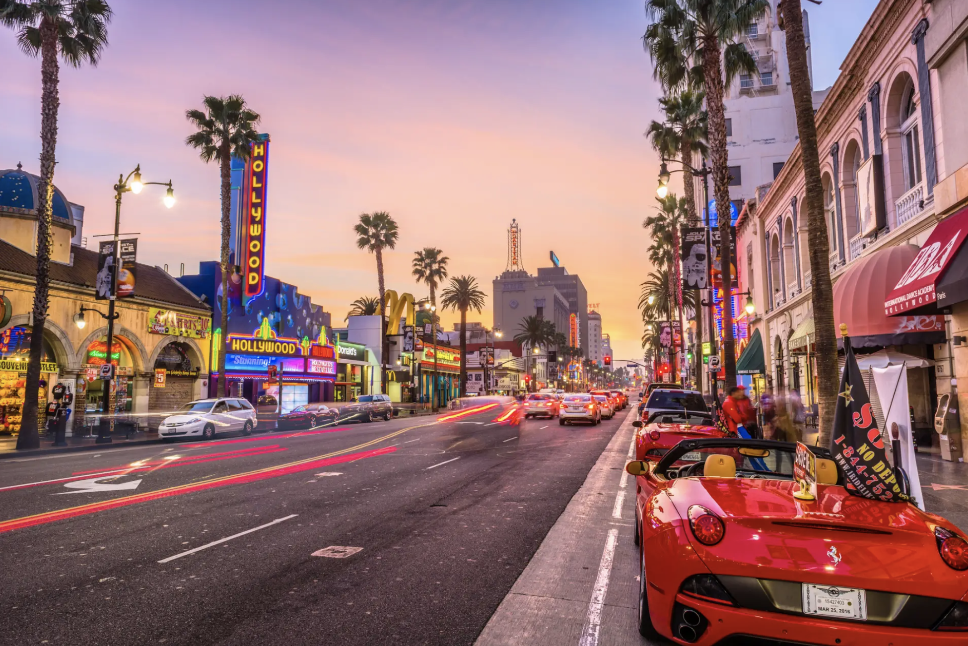 Busy street with neon lights and sunset colors in the sky, painting a beautiful picture of the lively culture along Hollywood Boulevard