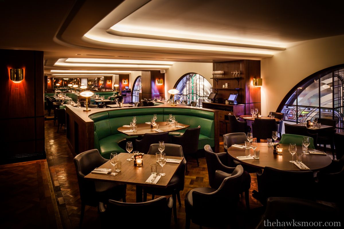 Dim lit restaurant with lowered table tops, booth seating  
