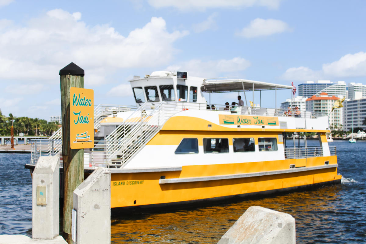 large two story yellow water taxi docked on the river