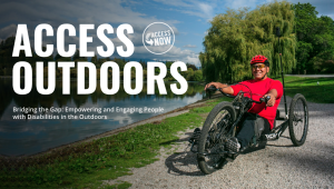 Image d'un autochtone en fauteuil roulant profitant d'un sentier naturel le long de l'eau avec son vélo à main.