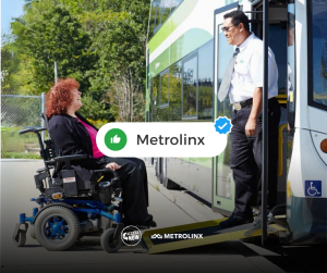 Power wheelchair user smiles as she drives onto a ramped bus greeting the driver