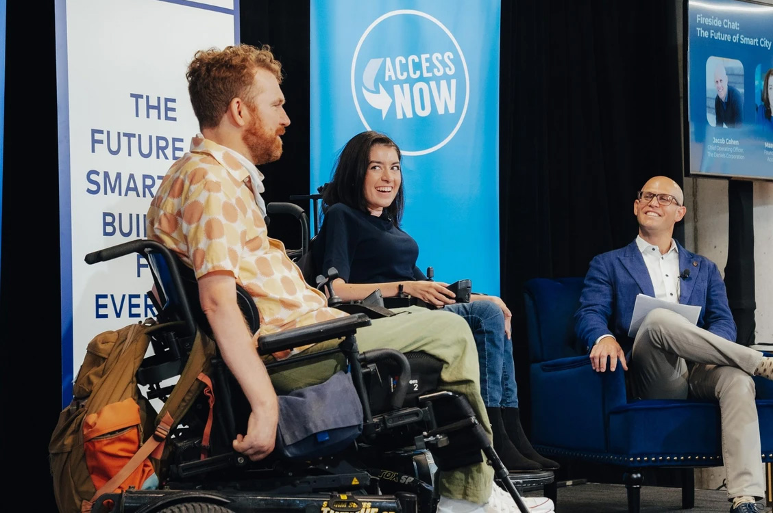 luke, maayan, and jake, sit on a stage sharing a panel discussion smiling.