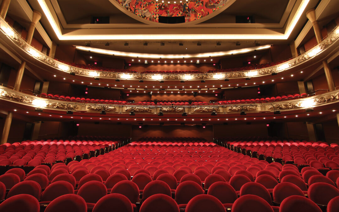 interior of grand princess of wales theatre. red seating and gold lighting.