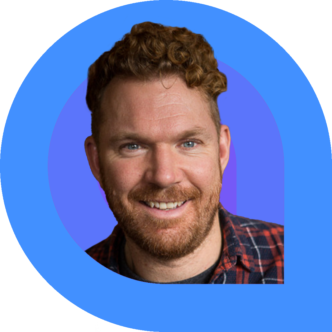 Luke Anderson, a man with short curly red hair and a beard, smiles warmly. He is wearing a red and navy plaid shirt. The portrait is framed by bold graphic rings in blue and purple on a vibrant pink background.