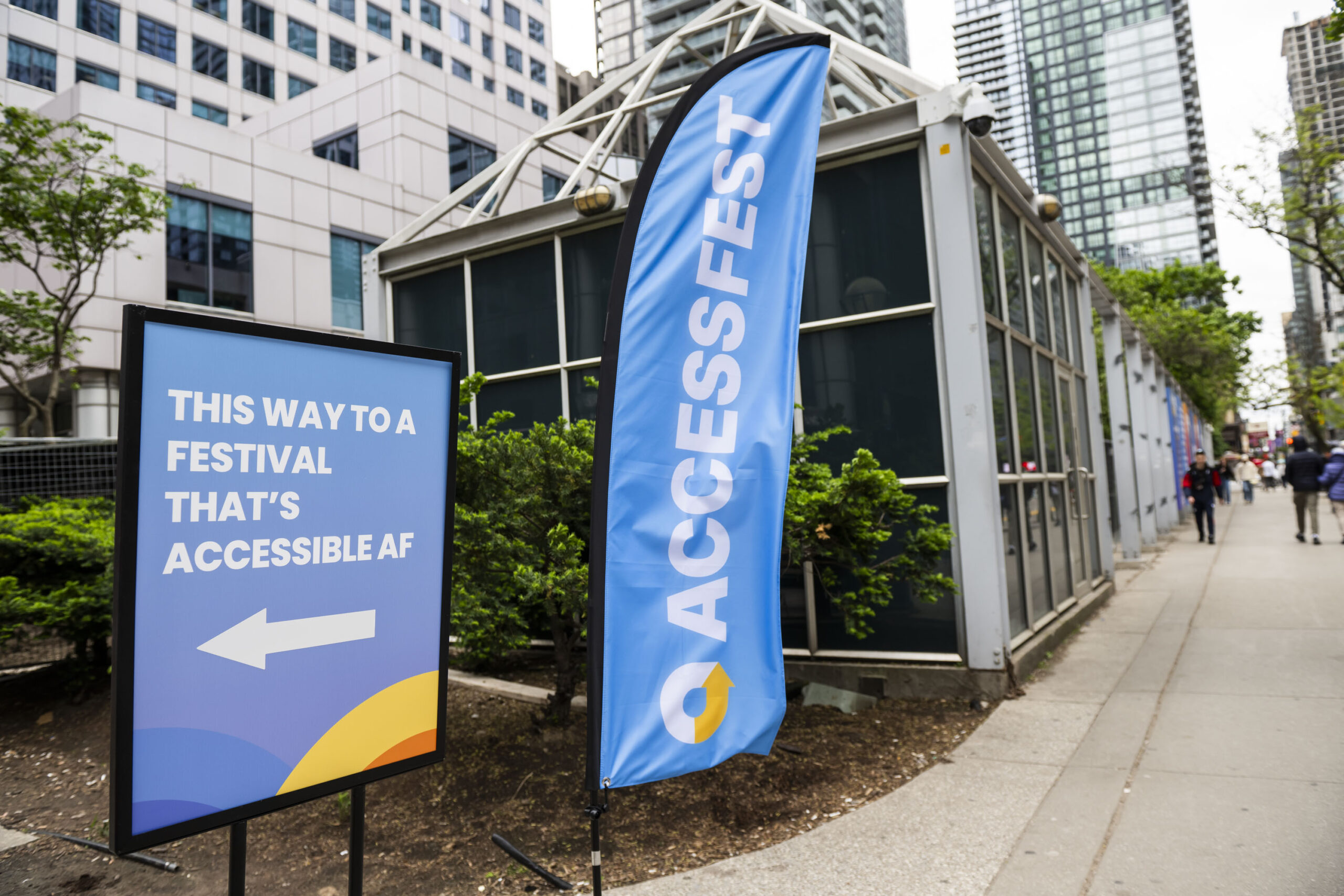 Outdoor signs from AccessFest. One reads "This way to a festival that's accessible AF", and the other reads "AccessFest". 