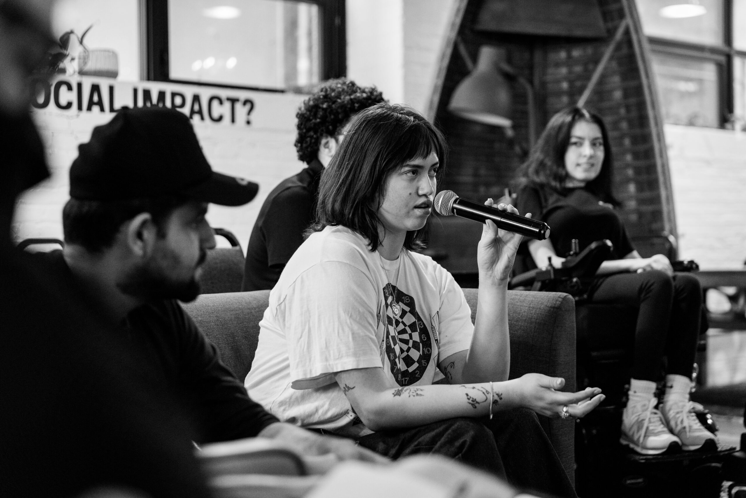 young woman holds microphone speaking in a group of youth