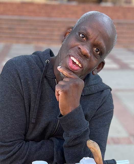 leroy moore sits on his scooter, smiling at the camera